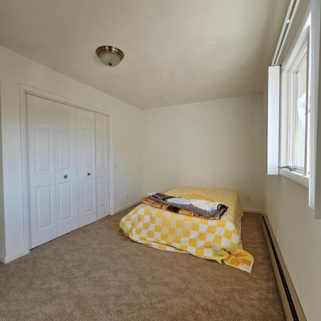 carpeted bedroom with baseboard heating and a closet