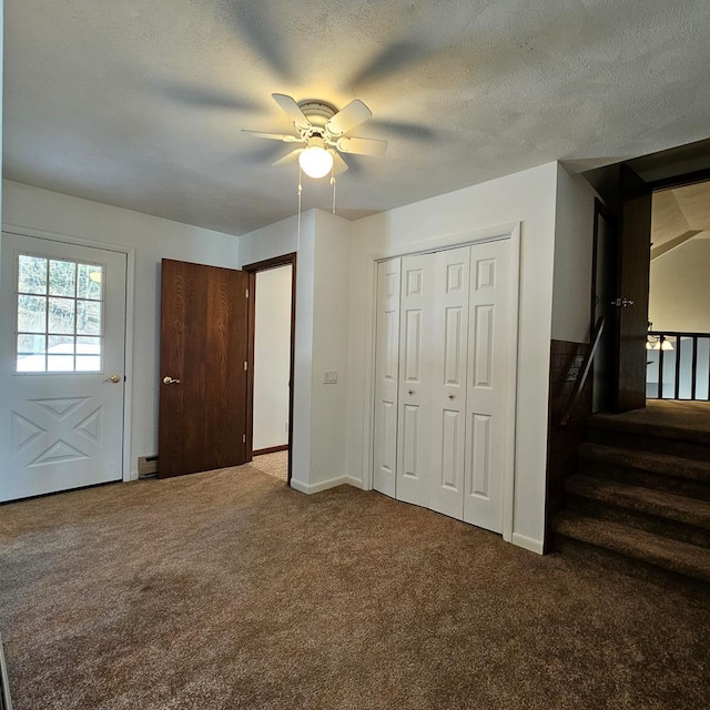 unfurnished bedroom featuring carpet flooring, a baseboard heating unit, ceiling fan, a textured ceiling, and a closet