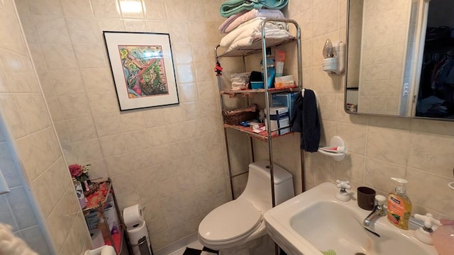 bathroom featuring toilet, tile walls, and sink