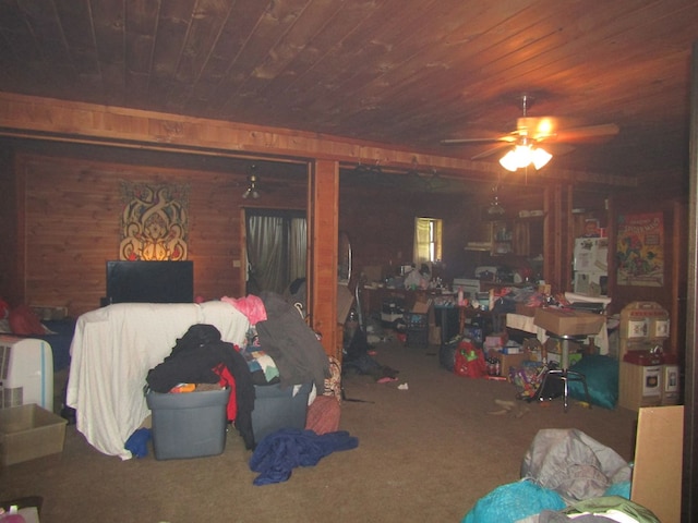 living room featuring carpet floors, ceiling fan, wooden walls, and wood ceiling