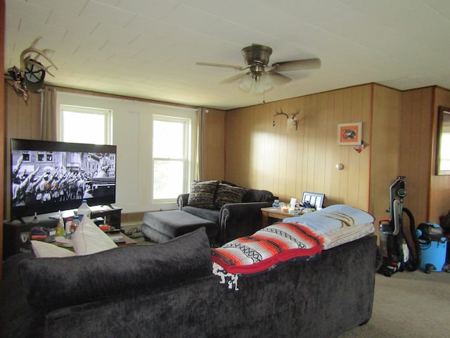 carpeted living room featuring ceiling fan and wood walls