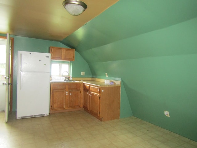 kitchen featuring white fridge, lofted ceiling, and sink