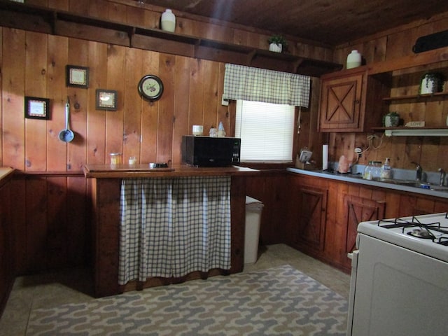 kitchen featuring wooden walls, sink, and white range with gas stovetop