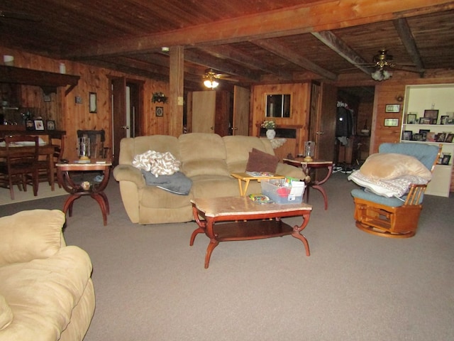 carpeted living room featuring ceiling fan, wood walls, wood ceiling, and beam ceiling