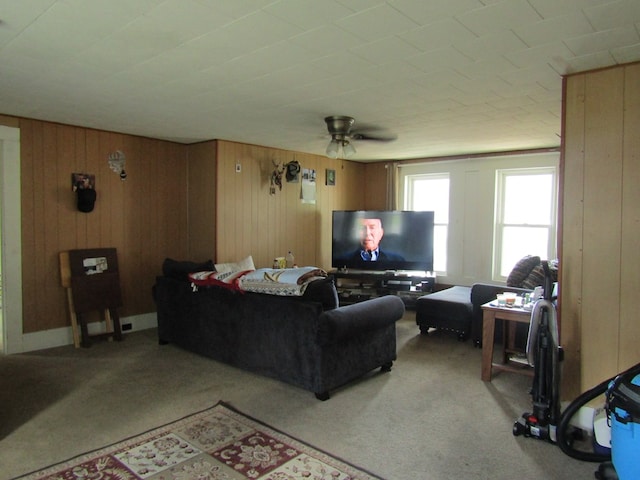 living room featuring light carpet, ceiling fan, and wood walls