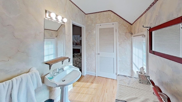 bathroom featuring hardwood / wood-style flooring, sink, crown molding, and vaulted ceiling