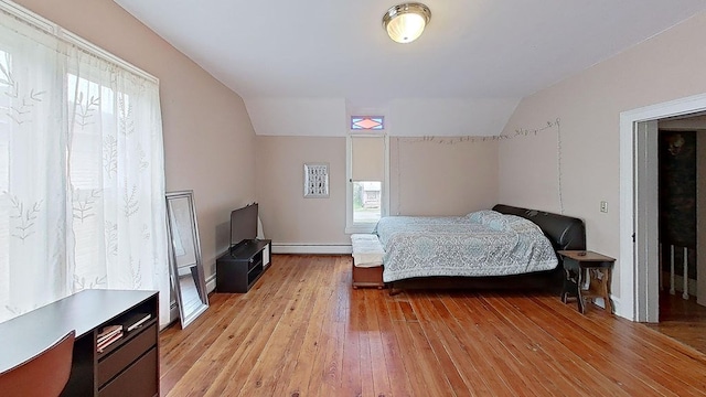 bedroom featuring vaulted ceiling, a baseboard radiator, and light hardwood / wood-style flooring