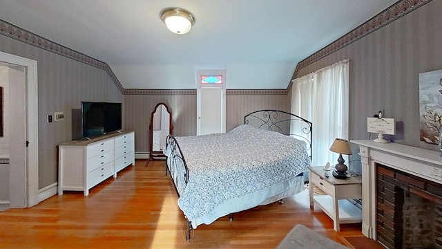 bedroom featuring light hardwood / wood-style floors and a brick fireplace