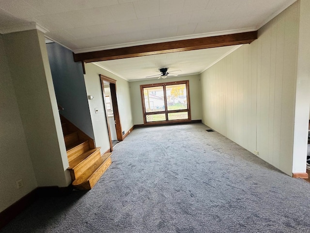 unfurnished room with carpet flooring, ceiling fan, wooden walls, crown molding, and beamed ceiling