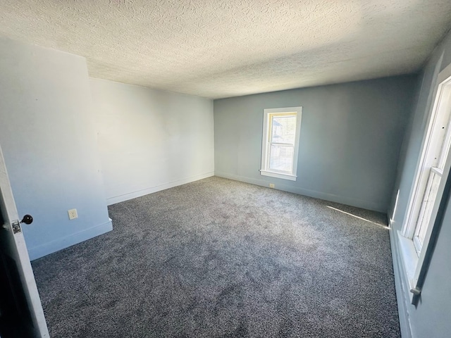 spare room with dark carpet and a textured ceiling