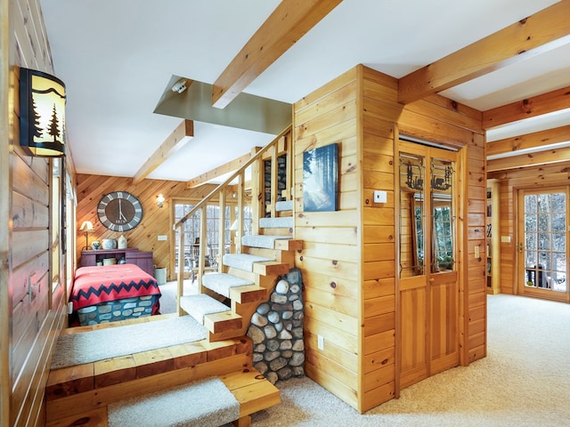 stairs featuring beam ceiling, wooden walls, and carpet