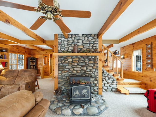 carpeted living room featuring ceiling fan, wooden walls, and beamed ceiling