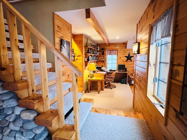 carpeted office featuring wood walls and beamed ceiling