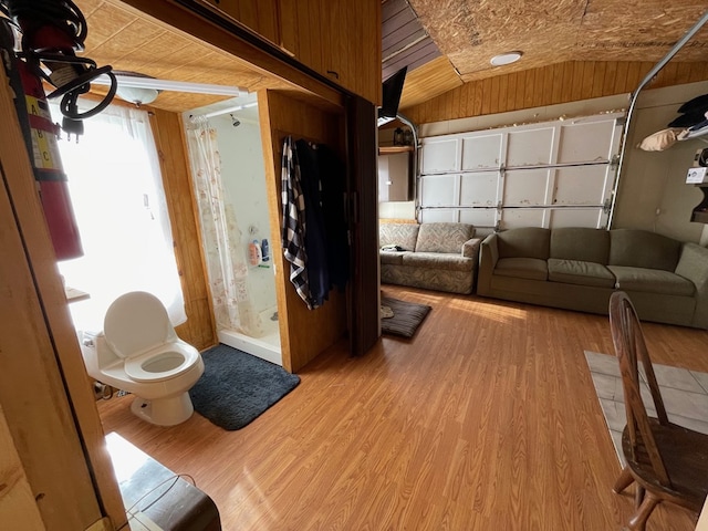 interior space featuring wooden walls, lofted ceiling, and light wood-type flooring