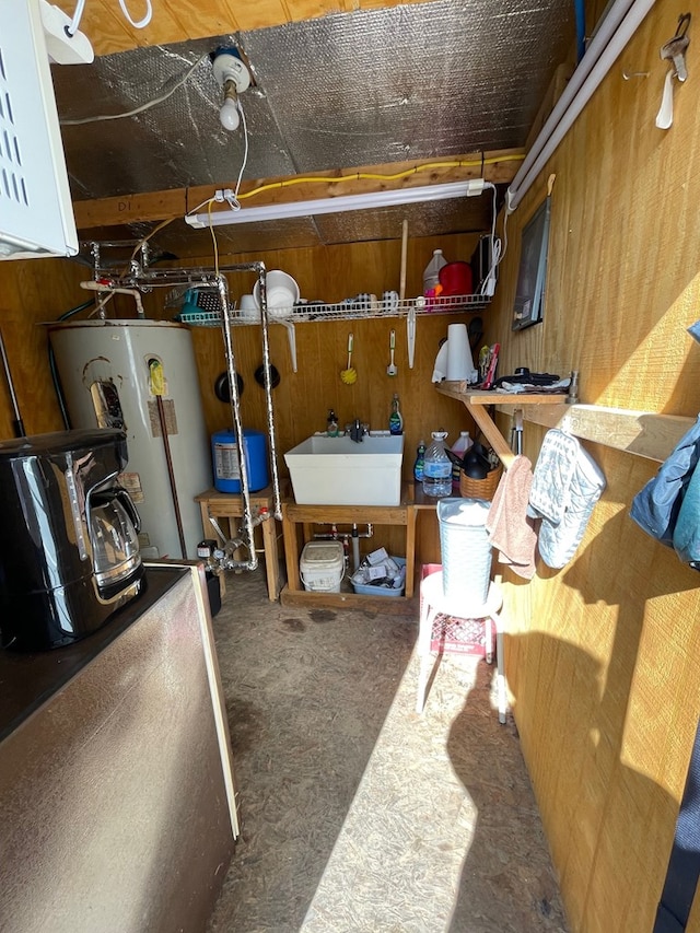 basement with gas water heater, wood walls, and sink