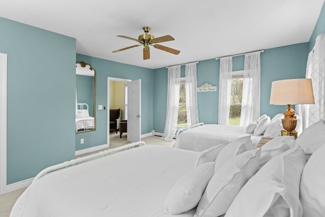 carpeted bedroom with baseboard heating, ceiling fan, and baseboards