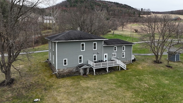 back of house with a yard, a deck with mountain view, stairway, and roof with shingles