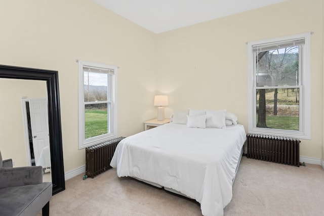 bedroom featuring radiator heating unit, multiple windows, and light carpet