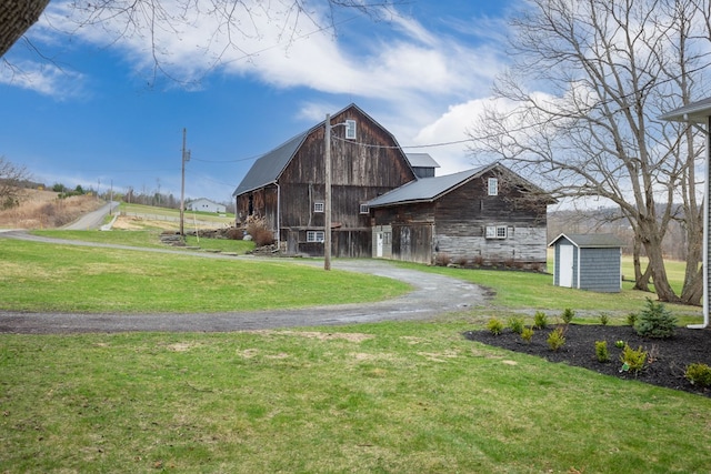 view of property's community with an outbuilding, a yard, a barn, and a storage unit