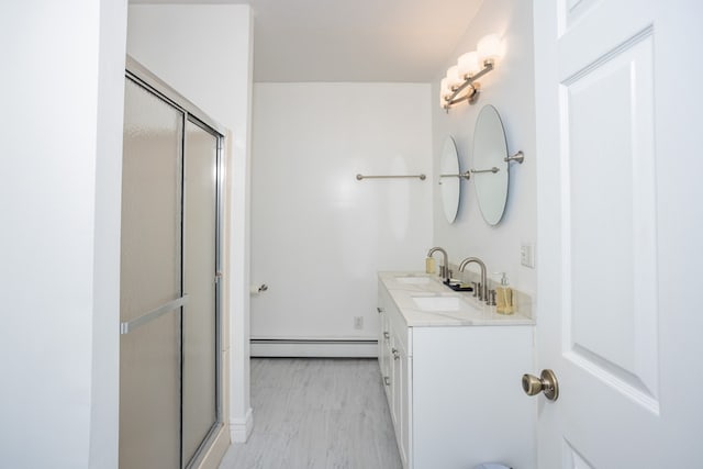 bathroom featuring a shower stall, a baseboard heating unit, baseboards, and vanity