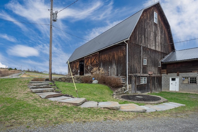 exterior space featuring a barn, a gambrel roof, an outbuilding, and metal roof