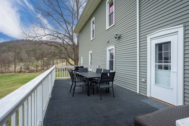 deck with outdoor dining area and a lawn