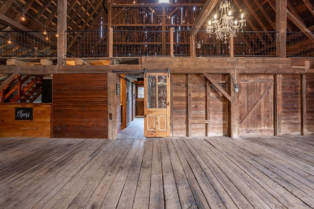 interior space with a chandelier, wooden walls, a towering ceiling, and hardwood / wood-style flooring