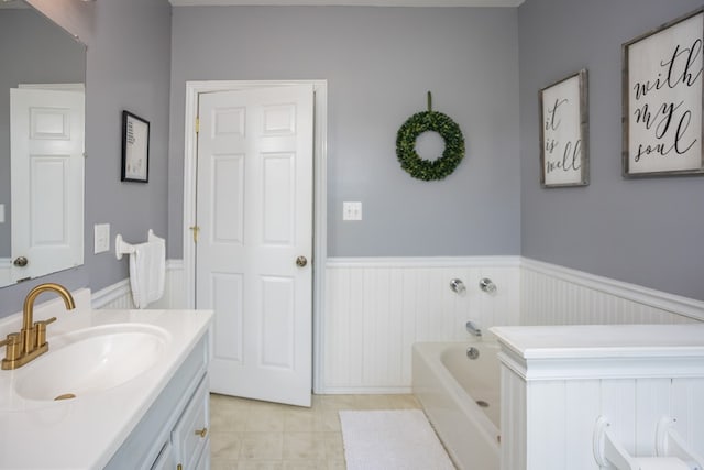 full bath featuring tile patterned flooring, a garden tub, wainscoting, and vanity