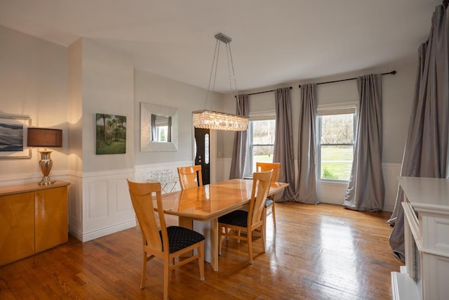 dining space featuring a decorative wall, a wainscoted wall, and wood finished floors