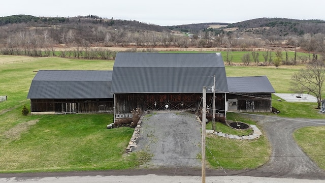 view of front of property featuring an outbuilding, aphalt driveway, metal roof, a barn, and a mountain view