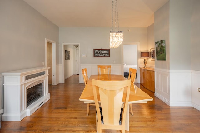 dining area featuring a wainscoted wall, a chandelier, and wood finished floors