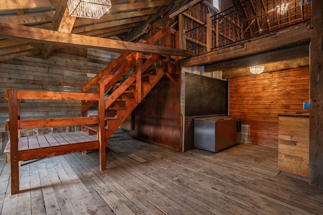 interior space with wood walls, lofted ceiling with beams, and hardwood / wood-style flooring