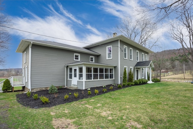 rear view of property with a yard, a sunroom, and a chimney