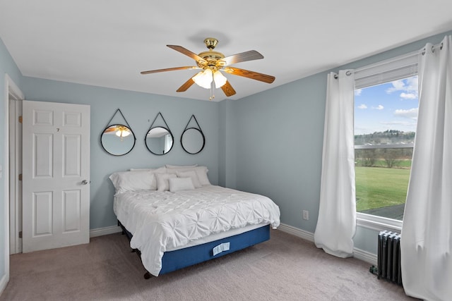 carpeted bedroom featuring radiator, ceiling fan, baseboards, and multiple windows