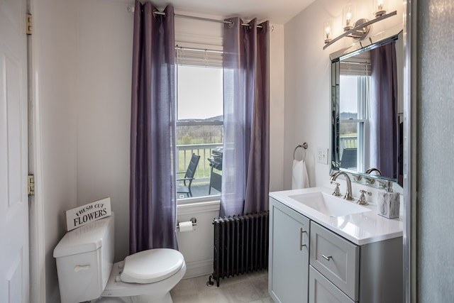 half bathroom with toilet, radiator, and vanity