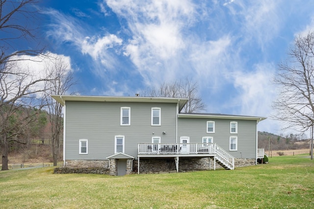 rear view of property with stairway, a wooden deck, and a lawn