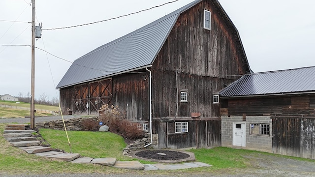 view of side of home featuring a barn, metal roof, a gambrel roof, and an outbuilding
