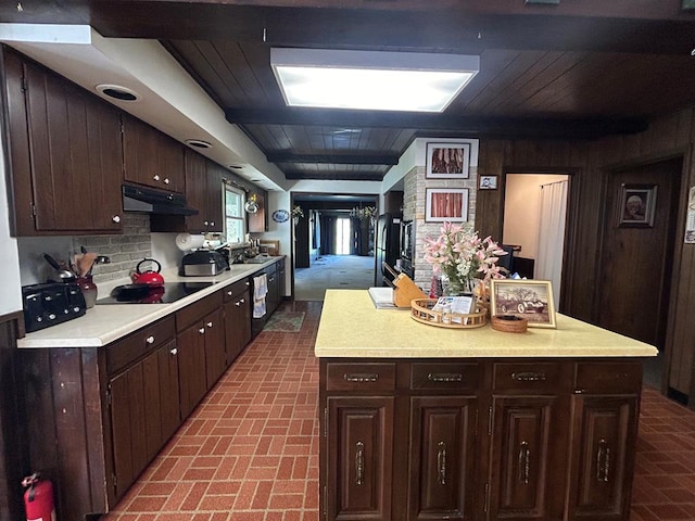 kitchen with black electric stovetop, dark brown cabinets, decorative backsplash, and wooden walls