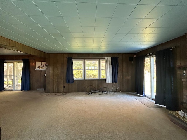 unfurnished living room featuring carpet flooring and wood walls