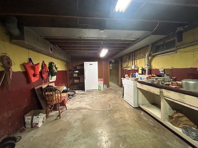 basement featuring a workshop area and white fridge