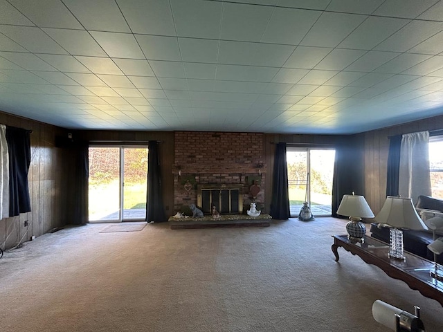 carpeted living room with a fireplace and wooden walls