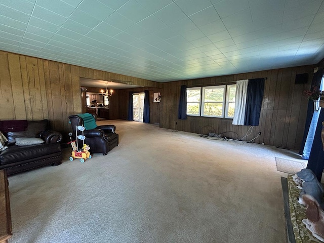 carpeted living room featuring wooden walls and an inviting chandelier