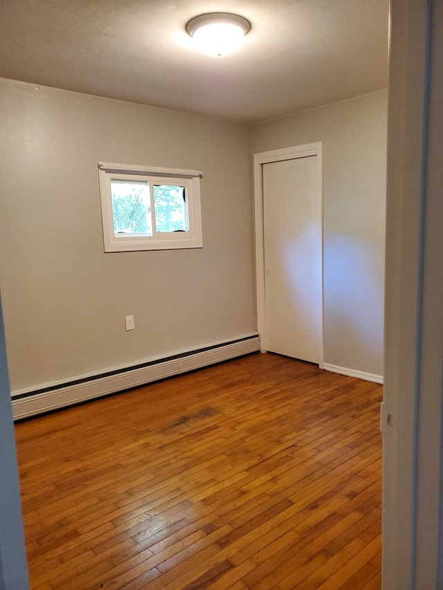 empty room featuring a baseboard radiator and wood-type flooring