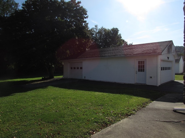 view of side of property featuring a lawn, an outdoor structure, and a garage