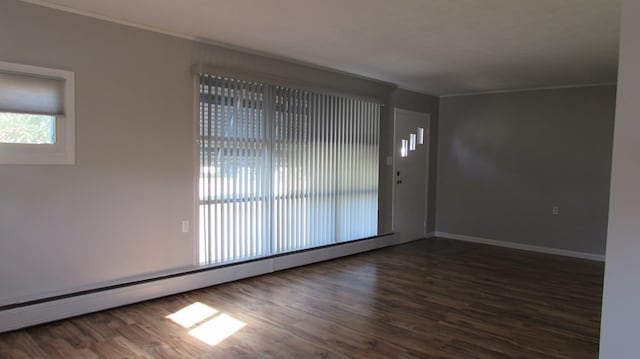 unfurnished room featuring a baseboard heating unit, ornamental molding, and dark wood-type flooring