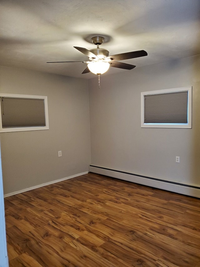 unfurnished room with ceiling fan, dark hardwood / wood-style floors, and a baseboard heating unit