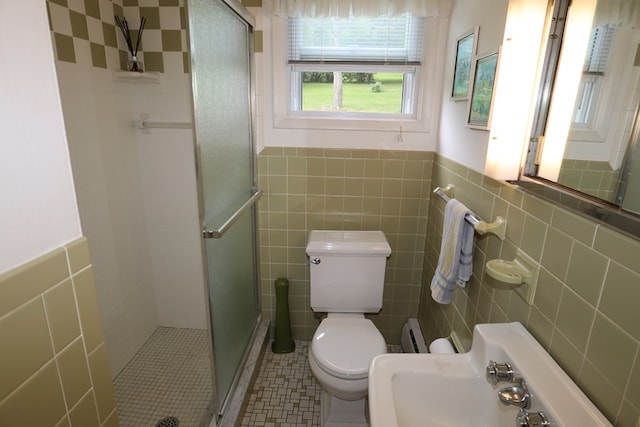1 Mechanic St, Towanda, PA 18848 - bathroom featuring tile walls, a shower stall, a baseboard radiator, wainscoting, and tile patterned flooring