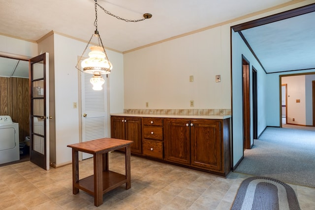 kitchen featuring light carpet, pendant lighting, ornamental molding, washer / clothes dryer, and light countertops