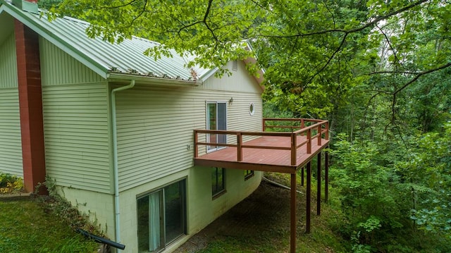 exterior space with a wooden deck, a chimney, and metal roof