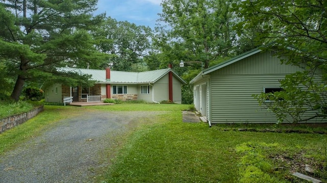 exterior space featuring driveway, metal roof, and a front lawn